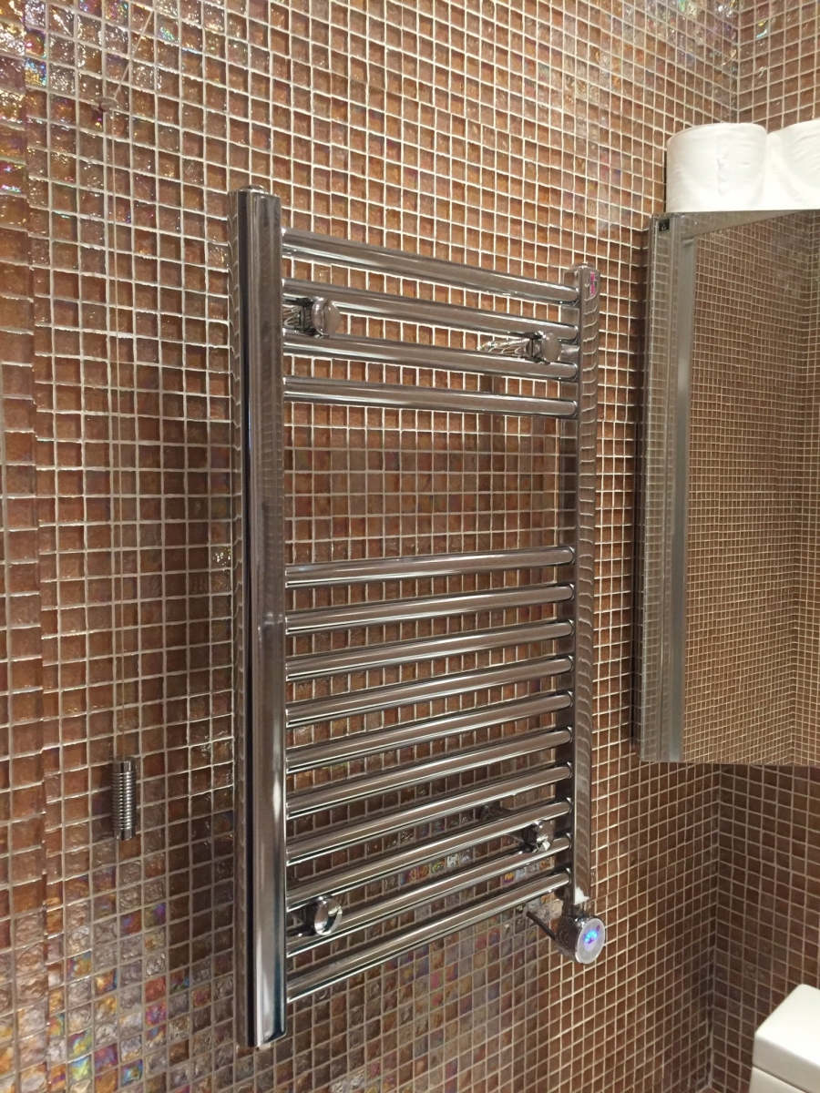 Electric heated towel rail installed in a tiled bathroom.